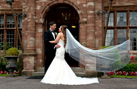 Bride-and-Groom-embrace-outside-Wrenbury-Hall-veil-extended-richard-linnett-photography