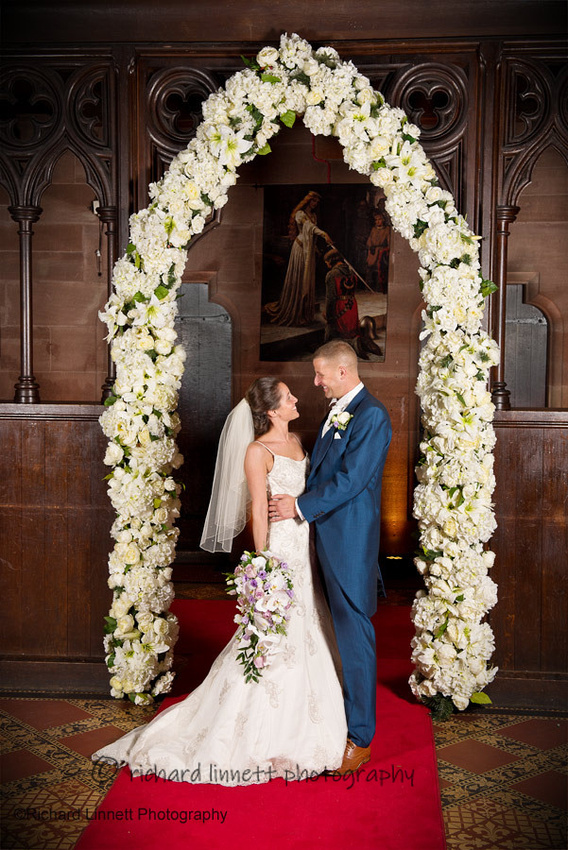 A King and Queen stand beneath a flowere arch